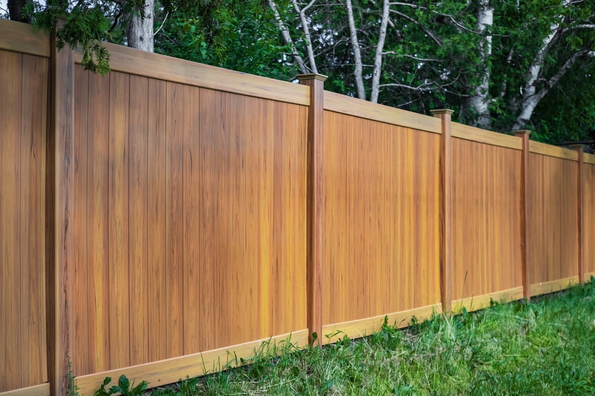 New residential wood privacy fence around a home with a green lawn